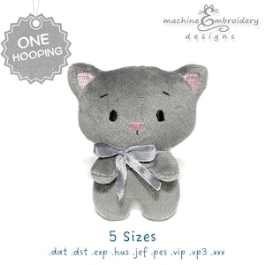 Op de afbeelding: Een grijze pluche kat met een zilveren strik, roze binnenoren en een roze neus. De kat heeft geborduurde gezichtskenmerken en staat rechtop. De afbeelding bevat de tekst "ONE HOOPING" en "5 Sizes".