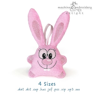 以下が含まれることがあります： 刺繍された目、鼻、口を持つピンクのフェルトのウサギ。ウサギは幸せそうな表情をしていて、小さな白いハートを持っています。「4サイズ」というテキストがウサギの下にあります。「.dat .dst .exp .hus .jef .pes .vip .vp3 .xxx」というテキストが「4サイズ」というテキストの下にあります。