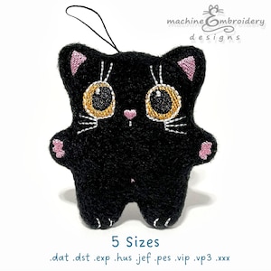 Op de afbeelding: Een zwart katvormig pluche ornament met geborduurde details. De kat heeft grote, gouden ogen, roze oren en poten en witte snorharen. Het ornament heeft een lus om op te hangen en de tekst "machine embroidery designs" is zichtbaar.