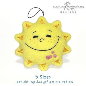 Pode incluir: Um sol amarelo sorridente com os olhos fechados e corações cor-de-rosa bordados na bochecha. O sol tem um laço para pendurar. O texto "machine embroidery designs" está no topo da imagem. O texto "5 Sizes" está na parte inferior da imagem. O texto ".dat .dst .exp .hus .jef .pes .vip .vp3 .xxx" está abaixo do texto "5 Sizes".