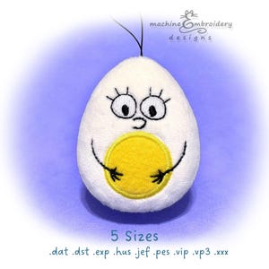 May include: A white plush egg-shaped character with a large yellow yolk center, black embroidered eyes, eyelashes, and arms. The text machineEmbroidery designs appears at the top, and 5 Sizes .dat .dst .exp .hus .jef .pes .vip .vp3 .xxx at the bottom.