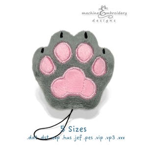 May include: A gray plush animal paw with pink embroidered pads and black claw details. The design features a black loop cord at the bottom. Text above reads machineEmbroidery designs and text below reads 5 Sizes .dat .dst .exp .hus .jef .pes .vip .vp3 .xxx.