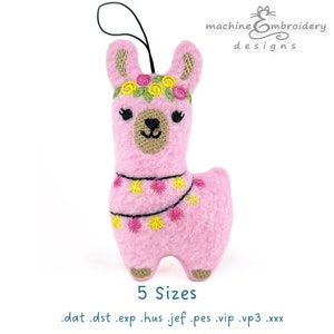 May include: A pink felt llama ornament with embroidered details. The llama has a floral crown and a garland of yellow and pink flowers. The ornament has a black string for hanging. The text "machine embroidery designs" is in the upper right corner.