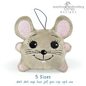 Pode incluir: Um rato de pelúcia cinza com orelhas cor-de-rosa e olhos pretos. O rato está sorrindo e tem um pequeno nariz. O rato é um design de bordado de máquina disponível em 5 tamanhos: .dat, .dst, .exp, .hus, .jef, .pes, .vip, .vp3, .xxx.