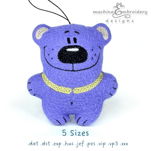 May include: Purple felt teddy bear with a yellow collar and a black nose. The bear is smiling and has a white highlight on its nose. The text "5 Sizes" and ".dat .dst .exp .hus .jef .pes .vip .vp3 .xxx" are below the bear.