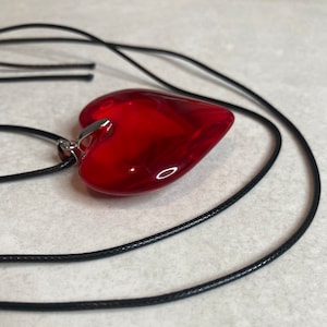 May include: A red heart-shaped pendant necklace with a black cord.