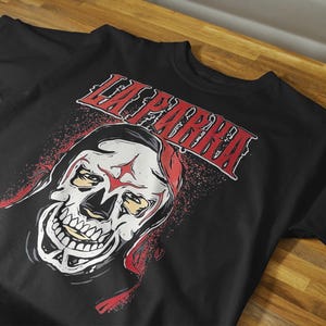 以下が含まれることがあります： 黒いTシャツ。赤い星と「LA PARRA」の文字が入ったスカルグラフィックが特徴です。スカルは白を基調とし、赤と黄色のアクセントがあります。文字は赤色で、白い縁取りがされています。