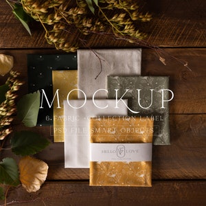 Puede incluir: Maqueta de seis muestras de tela con diferentes patrones, incluyendo diseños florales y geométricos. Las muestras están dispuestas sobre una superficie de madera con follaje otoñal. El texto "MOCKUP 6. FABRIC + COLLECTION LABEL PSD FILE SMART OBJECTS" es visible en la imagen.