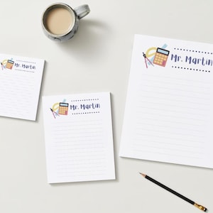 May include: Three white notepad sets with lined paper. The top notepad has a blue and white border with the text "Mr. Martin" and a cartoon illustration of a calculator, protractor, and pencil. The middle notepad has a blue and white border with the text "Mr. Martin" and a cartoon illustration of a calculator, protractor, and pencil. The bottom notepad has the text "Mr. Martin" in a blue and white border.