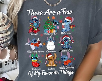 May include: A gray t-shirt with a blue cartoon character design. The text on the shirt reads "These Are a Few Of My Favorite Things" and lists Christmas-themed items like presents, a Christmas tree, hot cocoa, Christmas movies, a snowman, holiday decor, stockings, cookies, and ugly sweaters.