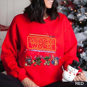 A woman wearing a red sweater with a Star Wars logo and characters on it, holding a small snowman.