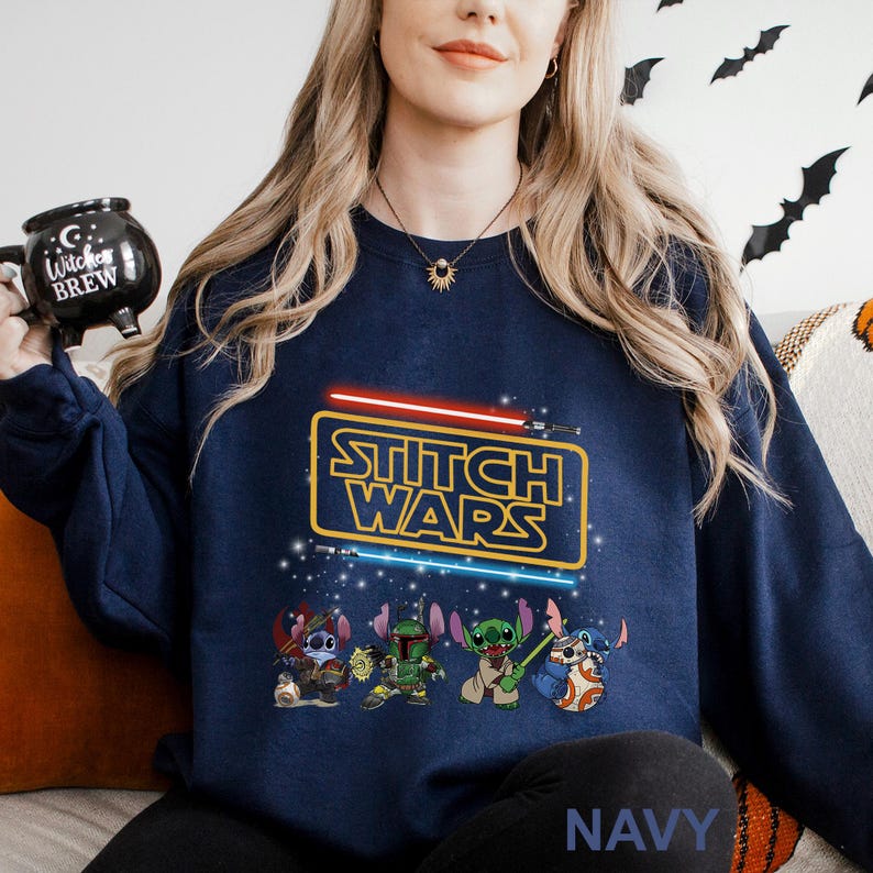 A woman wearing a navy blue sweatshirt with a Star Wars logo and characters printed on it, holding a black mug with a Star Wars design.