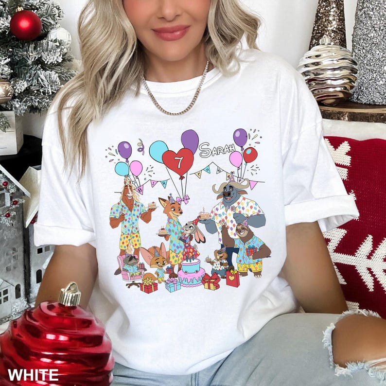 A woman wearing a white t-shirt with a graphic design of cartoon animals celebrating a birthday.