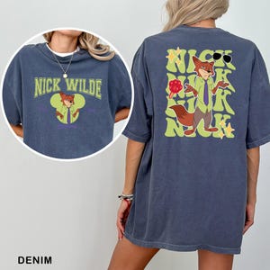 A denim t-shirt with a graphic of a cartoon fox character and text that says "NICK WILDE" and "2010".