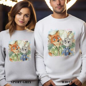 Two people wearing white sweatshirts with cartoon images of a fox and a rabbit.