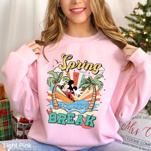 A woman wearing a pink sweatshirt with a cartoon character and the text "Spring Break" printed on it.