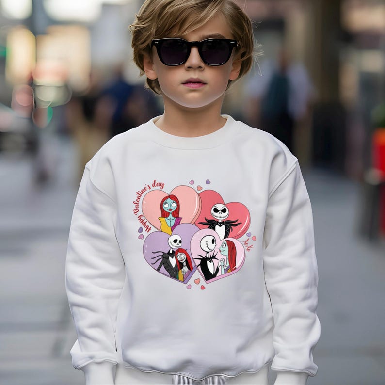 A young boy wearing a white sweatshirt with a graphic of characters from the movie " Nightmare Before Christmas" and sunglasses.