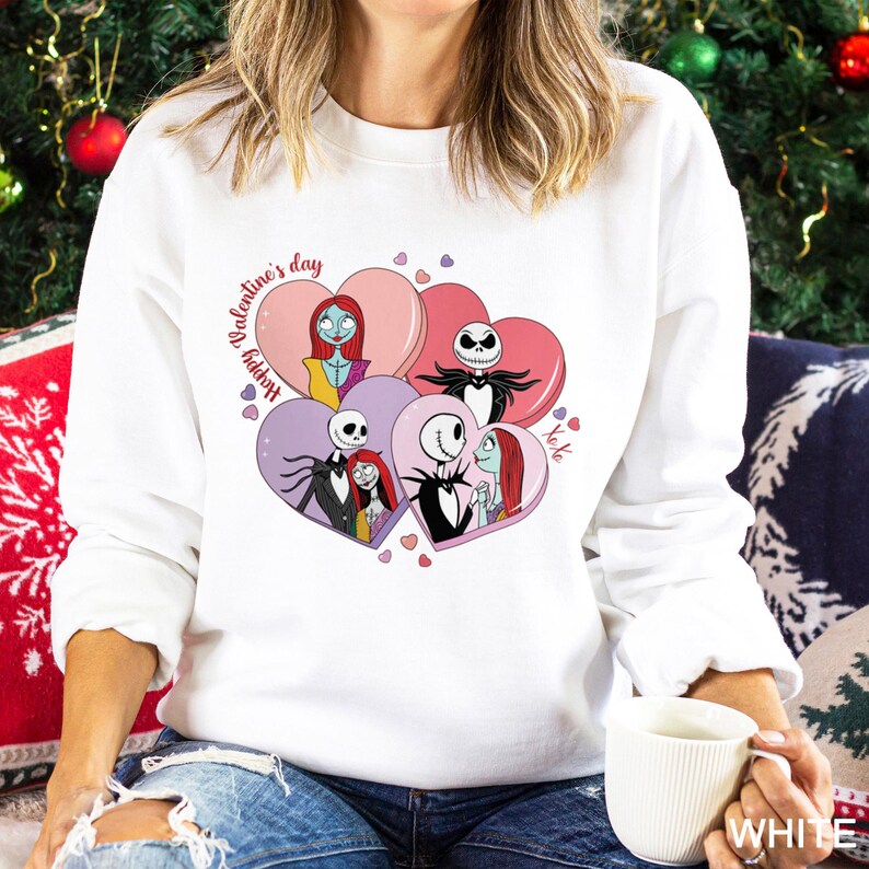 A woman wearing a white sweater with a graphic design featuring characters from the movie " Nightmare Before Christmas".