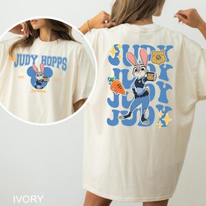 A woman wearing a white t-shirt with a graphic of a cartoon rabbit character and text related to the character Judy Hopps.