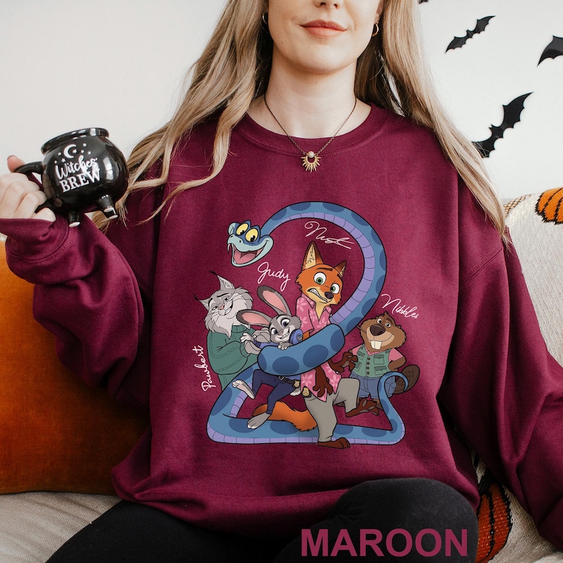 A woman wearing a maroon sweater with a cartoon character design, holding a black mug with a cartoon character on it.