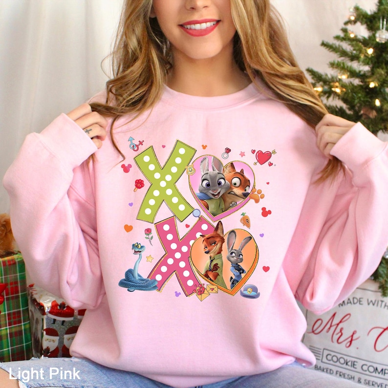 A woman wearing a pink sweatshirt with a cartoon character design on it.
