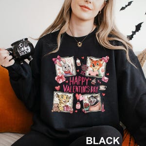 A woman wearing a black sweatshirt with a graphic design featuring cartoon animals and the text "Happy Valentine's Day".