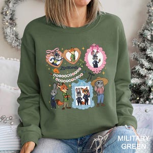 A woman wearing a green sweatshirt with a collage of cartoon animal characters and a pink frame.