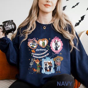 A woman wearing a navy blue sweatshirt with a graphic of cartoon animals, including a fox, rabbit, and duck, along with the text "Zoooria" and "Welcome to Zoooria".