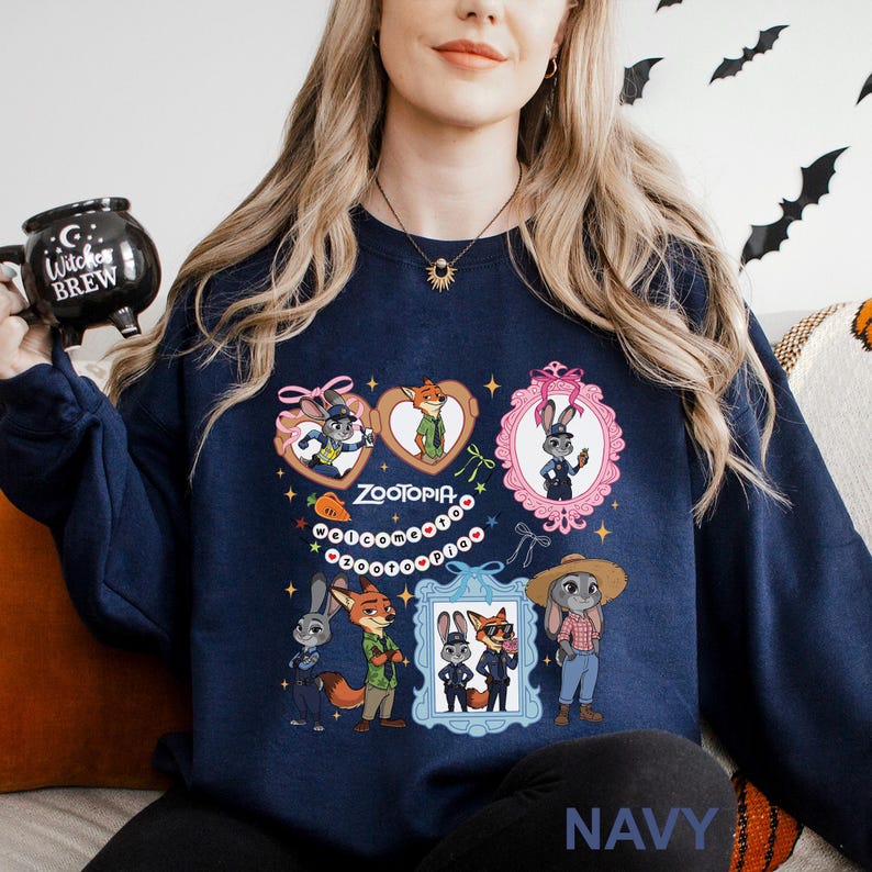 A woman wearing a navy blue sweatshirt with a graphic of cartoon animals, including a fox, rabbit, and duck, along with the text "Zoooria" and "Welcome to Zoooria".