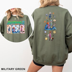 A woman wearing a green sweatshirt with a colorful graphic of various cartoon characters and a military-style design on the back.