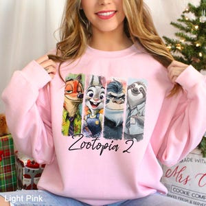 A woman wearing a pink sweatshirt with a graphic of four cartoon animal characters from the movie Zootopia.
