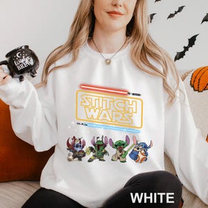 A woman wearing a white sweatshirt with a Star Wars logo and characters printed on it.