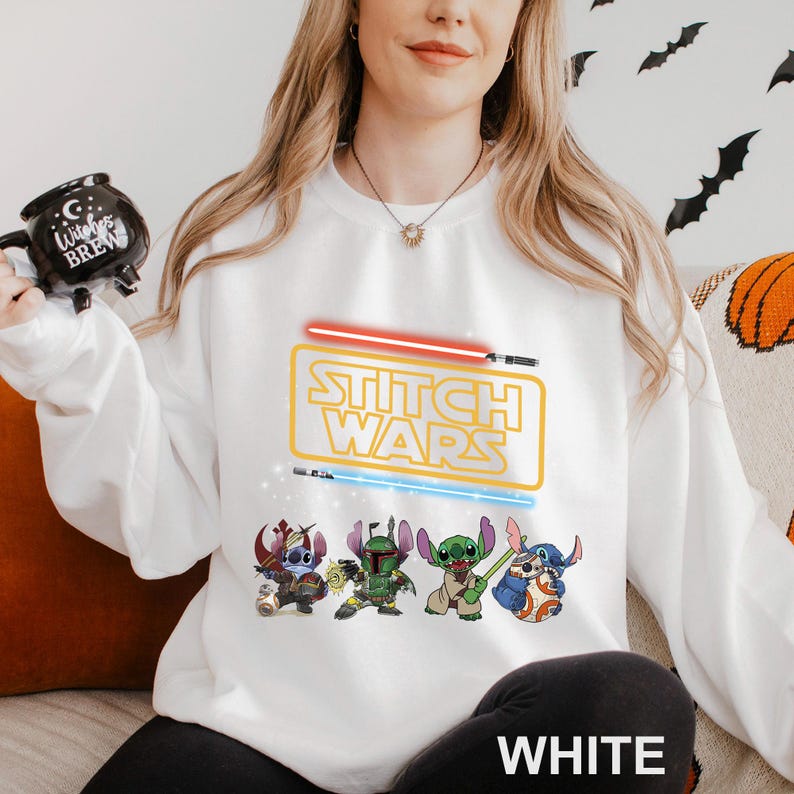A woman wearing a white sweatshirt with a Star Wars logo and characters printed on it.