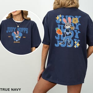 A woman wearing a navy blue t-shirt with a graphic of a cartoon rabbit character and text related to the character Judy Hopps.