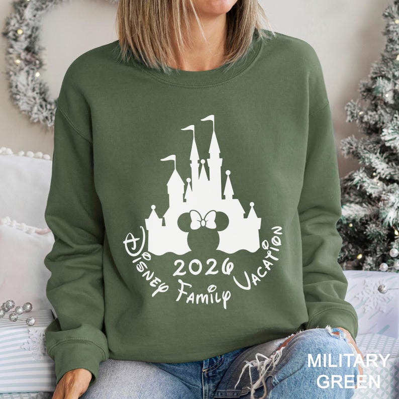 A woman wearing a green sweatshirt with a white graphic of a castle and the text "Disney 2020 Family Vacation" printed on it.