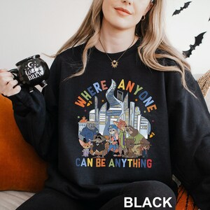 A woman wearing a black sweatshirt with a colorful graphic design and text printed on it.