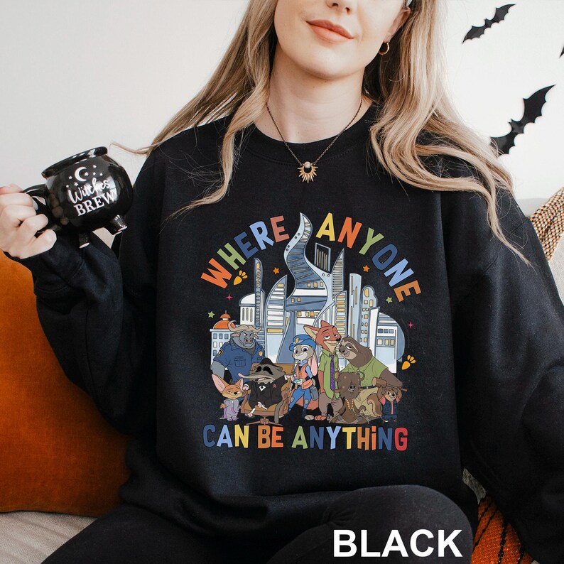 A woman wearing a black sweatshirt with a colorful graphic design and text printed on it.