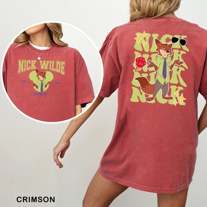 A red t-shirt with a cartoon image of a fox wearing sunglasses and holding a red flower.