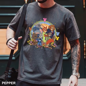 A person wearing a gray t-shirt with a colorful graphic of cartoon characters from the Disney movie "Jurassic Park".