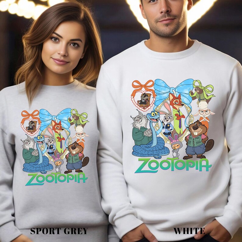 Two people wearing white sweatshirts with a colorful cartoon character design featuring various animals and the word "Zootopia".