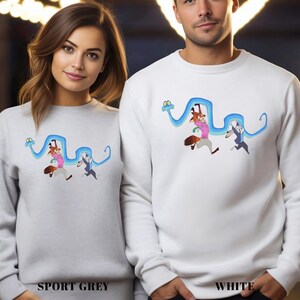 Two people wearing white sweatshirts with cartoon characters on them.