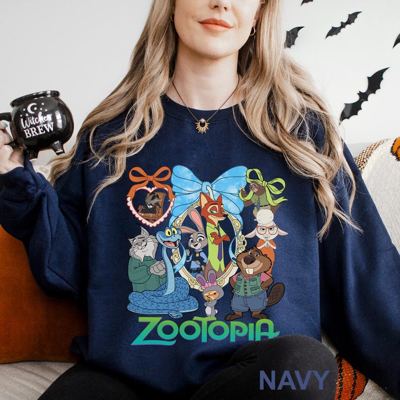 A woman wearing a navy blue sweatshirt with a cartoon character design, including a cat, dog, and other animals, along with the text "Zootopia". She is holding a black mug with the text "Cup of Wookiee Brew" printed on it.