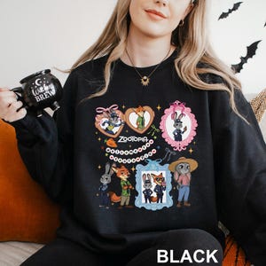 A woman wearing a black sweatshirt with a graphic design featuring cartoon characters and a mug.