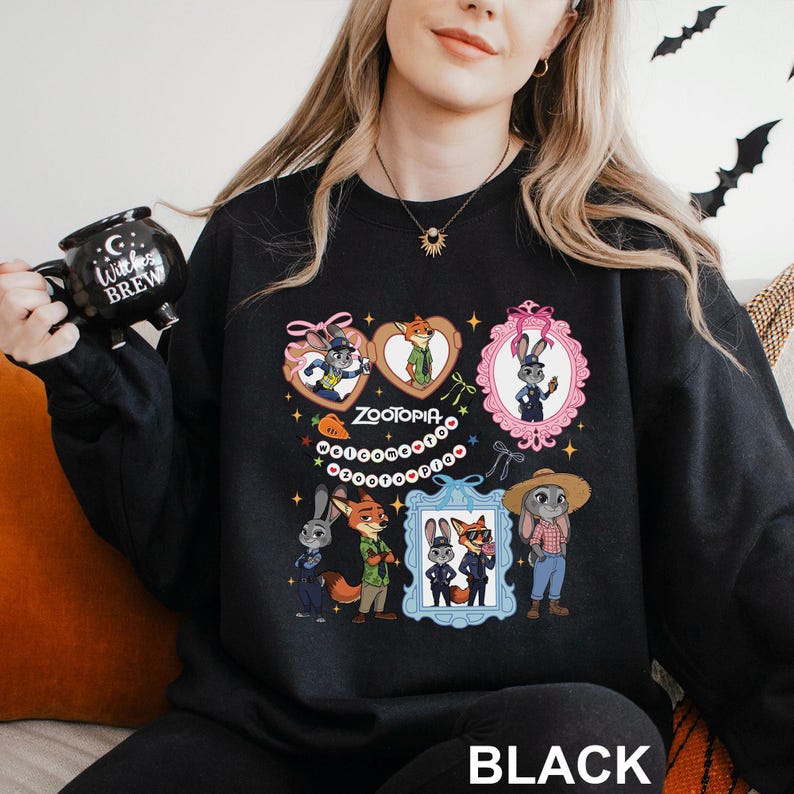 A woman wearing a black sweatshirt with a graphic design featuring cartoon characters and a mug.