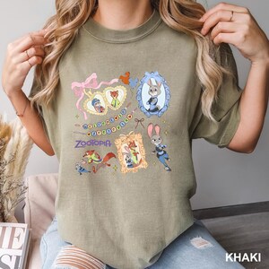 A woman wearing a green t-shirt with various cartoon animal characters and a decorative frame design.