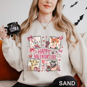 A woman wearing a white sweatshirt with a graphic design featuring cartoon animal characters and the text "Happy Valentine's Day".