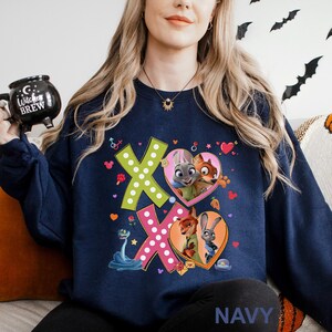 A woman wearing a navy blue sweatshirt with a graphic design featuring cartoon animal characters and a large "X" in the center.
