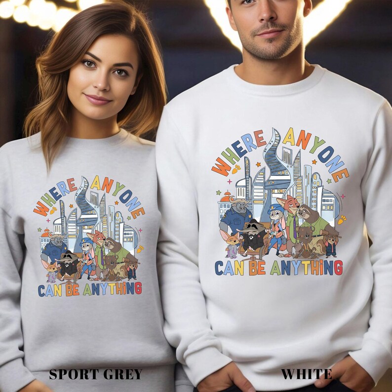 Two people wearing matching white sweatshirts with a colorful graphic design featuring cartoon characters and text.