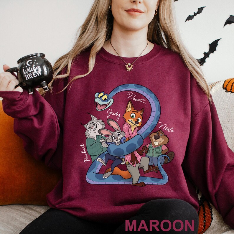 A woman wearing a maroon sweater with a cartoon character design, holding a black mug with a cartoon character on it.