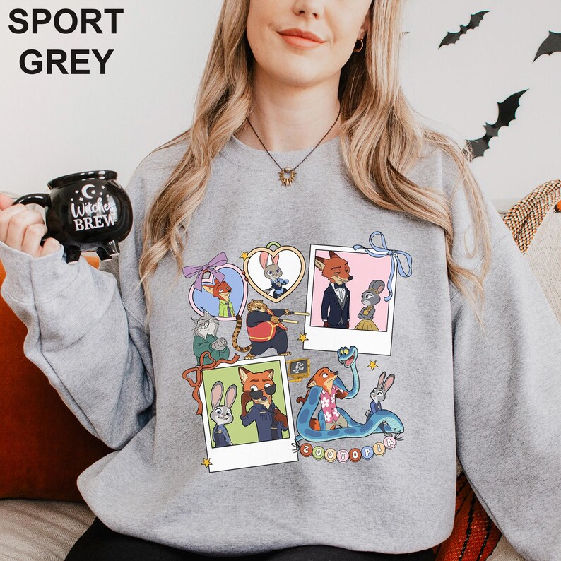A woman wearing a grey sweatshirt with a collage of cartoon animal characters on it, holding a black mug with the text "I love JUDGE BREW" printed on it.